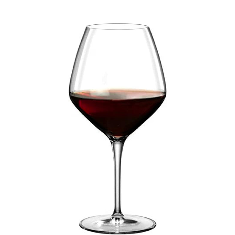 Calice di vetro trasparente a stelo lungo con vino rosso fino a metà altezza, sfondo bianco neutro.