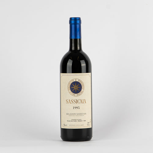bottiglia di vino rosso Sassicaia 1995 con etichetta beige e tappo blu su sfondo bianco