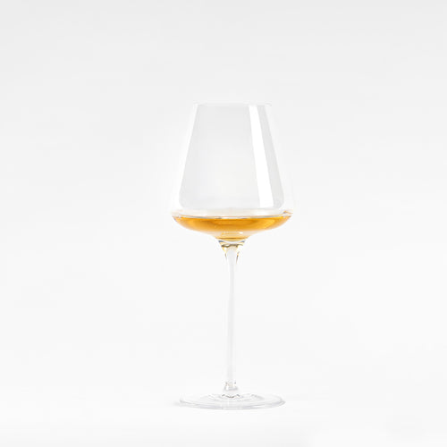Calice di vino trasparente con gambo lungo, contenente liquido dorato, su sfondo bianco.