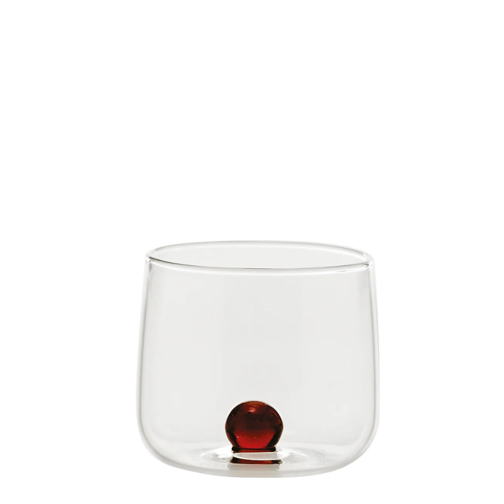 bicchiere trasparente in vetro con base piatta e sfera decorativa rossa alla base, su sfondo bianco semplice