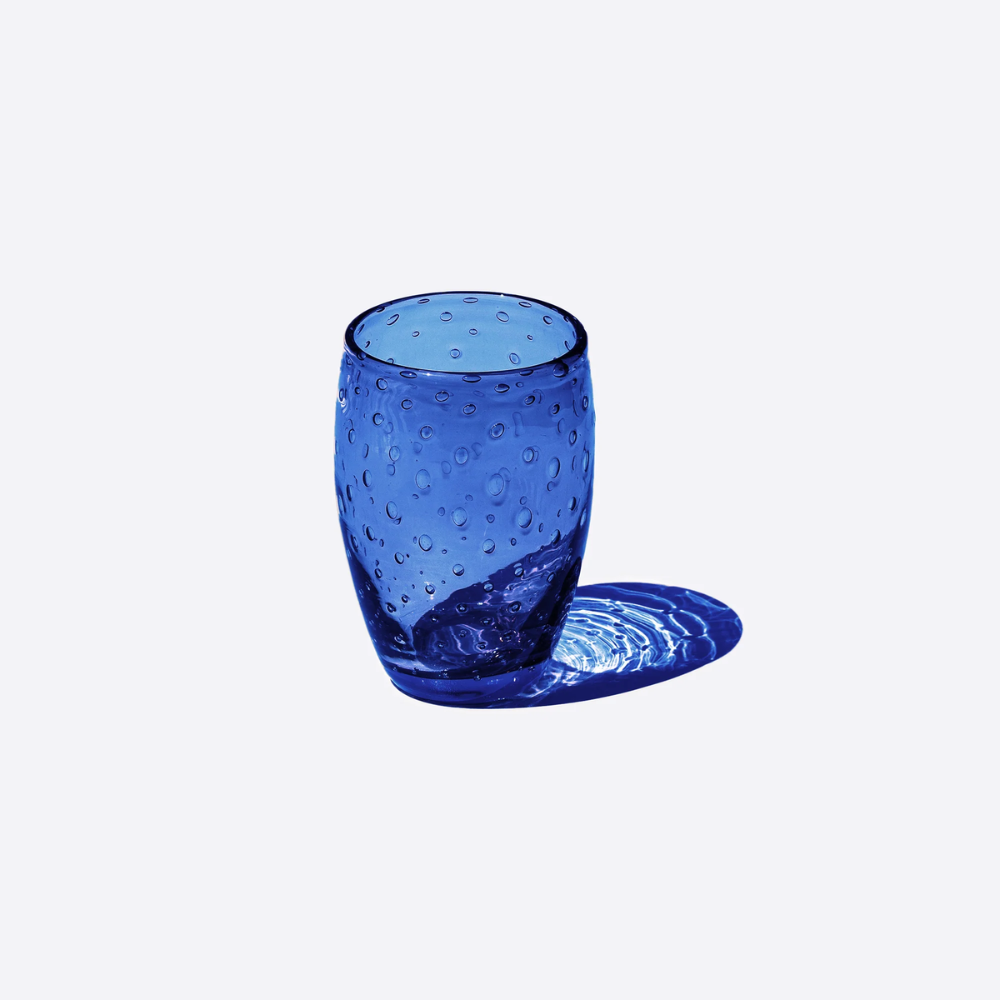 bicchiere blu in vetro trasparente con bolle, forma cilindrica arrotondata, ombra sul lato destro, sfondo bianco