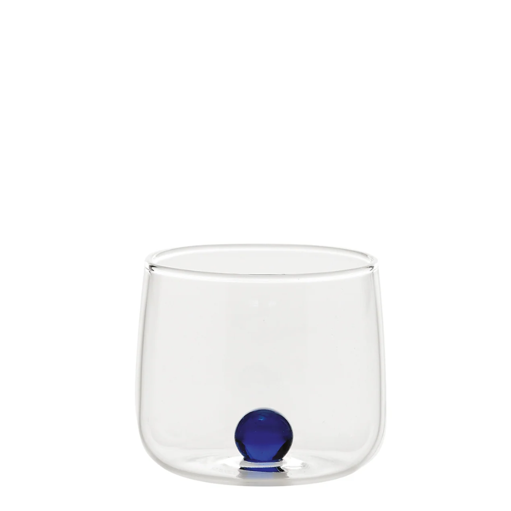 Bicchiere trasparente in vetro con base rotonda e sfera blu decorativa all'interno, sfondo bianco.