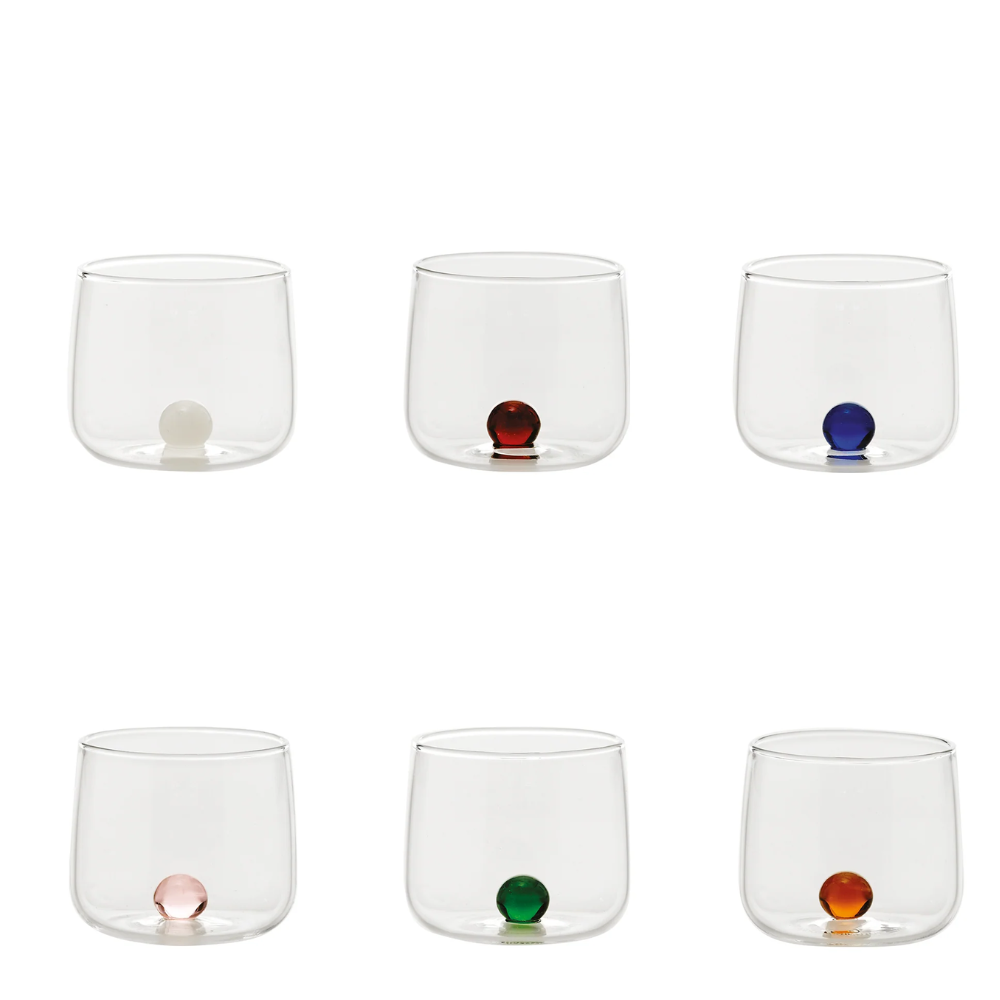 Sei bicchieri trasparenti in vetro con base tonda, ciascuno con una sfera colorata alla base: bianca, rossa, blu, rosa, verde e arancione.