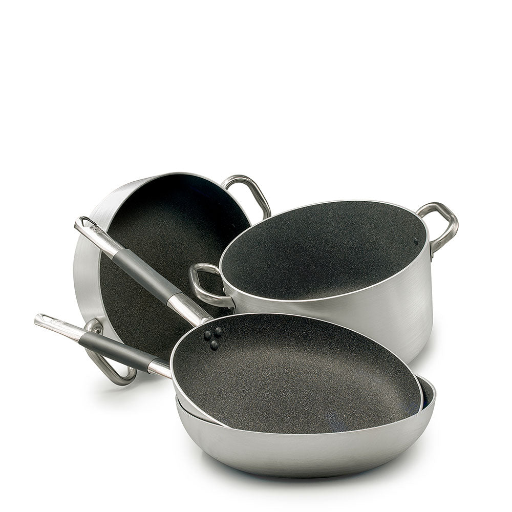 Set di pentole e padelle in acciaio inox con rivestimento interno antiaderente nero, manici in metallo e silicone grigio, su sfondo bianco.