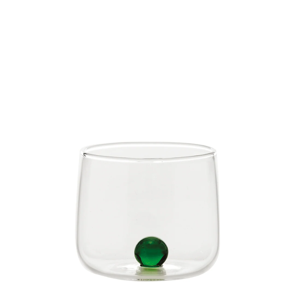 bicchiere trasparente in vetro con base rotonda e sfera verde decorativa all’interno su sfondo bianco