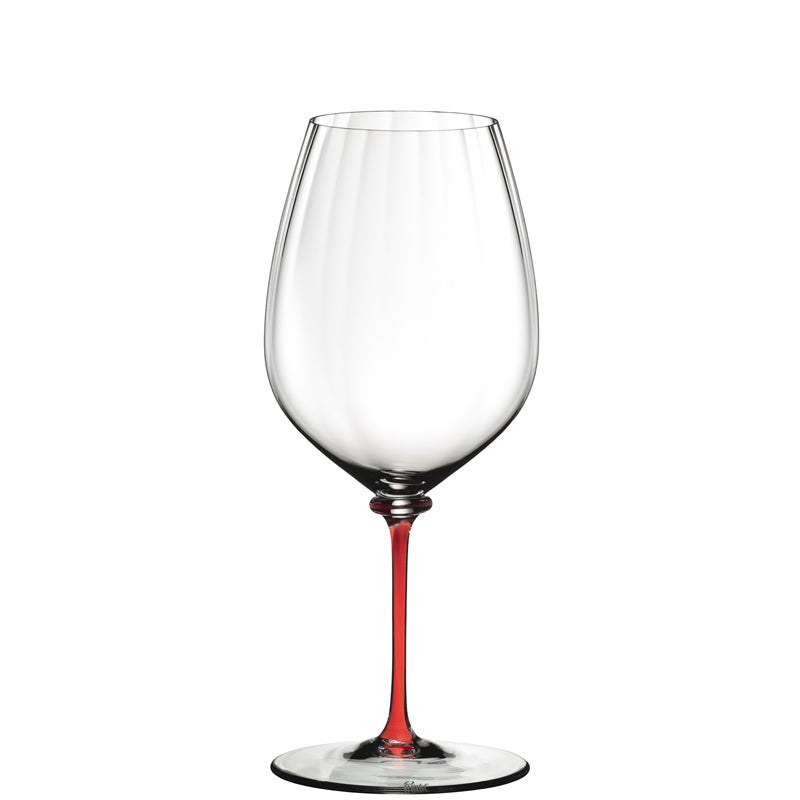 Calice da vino in vetro trasparente con gambo sottile di colore rosso isolato su sfondo bianco.