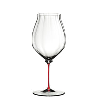 Calice da vino trasparente con stelo sottile di colore rosso, su sfondo bianco.