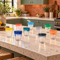 Vasos de agua degradados en varios colores sobre mesa puesta ambiente suave cálido y acogedor