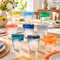 Vasos de agua degradados en varios colores sobre mesa puesta ambiente suave cálido y acogedor