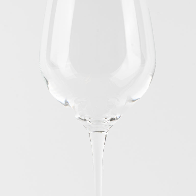Calice da vino trasparente in vetro con gambo lungo su sfondo bianco uniforme.