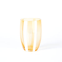 Bicchiere di vetro trasparente arancione con righe verticali bianche, superficie lucida, sfondo bianco minimalista.