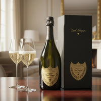 bottiglia di champagne Dom Pérignon vintage 2013 verde con etichetta dorata accanto a due flute di vetro pieni e confezione nera con logo dorato su
