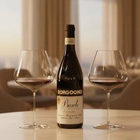 Bottiglia di vino rosso Borgogno Barolo 2018 in vetro scuro con due calici di vino rosso su tavolo in ambiente interno elegante.