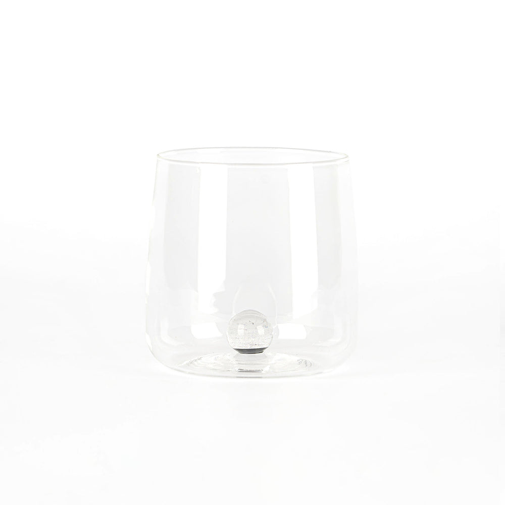 bicchiere trasparente in vetro con fondo doppio sferico interno, sfondo bianco uniforme senza altri elementi visibili
