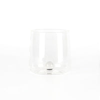 bicchiere trasparente in vetro con fondo doppio sferico interno, sfondo bianco uniforme senza altri elementi visibili