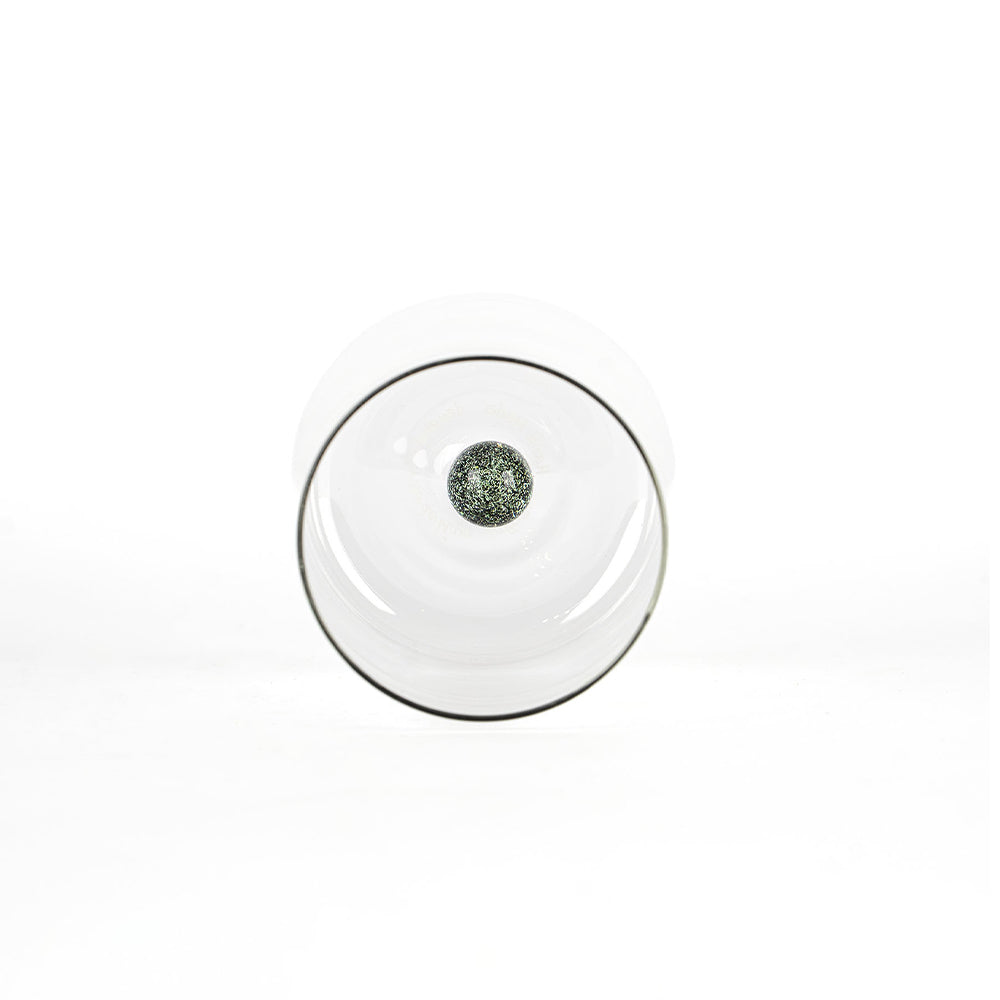 bicchiere trasparente con base tonda e sfera verde scuro decorativa al centro, sfondo bianco pulito