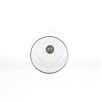 bicchiere trasparente con base tonda e sfera verde scuro decorativa al centro, sfondo bianco pulito