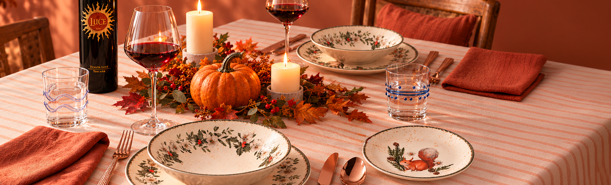 Autumn table with wine, glasses, candles, a pumpkin and a decorated dinner service