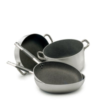 Set di pentole e padelle in acciaio inox con rivestimento interno antiaderente nero, manici in metallo e silicone grigio, su sfondo bianco.